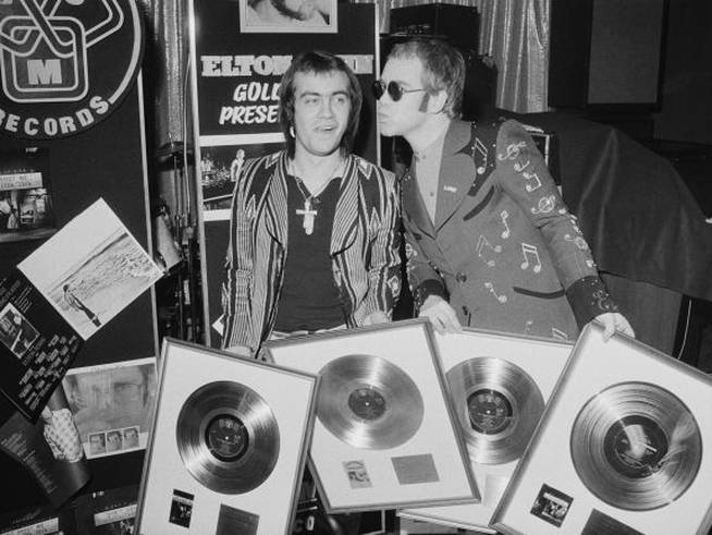 Elton John y su colaborador Bernie Taupin, recogiendo cuatro discos de oro como reconocimiento a su trabajo, en 1973.
