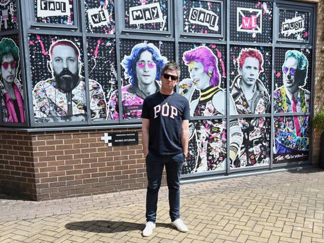 Noel Gallagher posa delante del mural en el que que están sus músicos favoritos: Bob Dylan, Andy Weatherall, David Bowie, John Lydon, John Lennon y Tony Wilson.