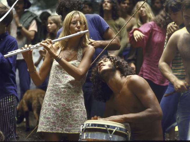 Asistentes al festival Woodstock bailan y tocan el timbal y la flauta travesera.