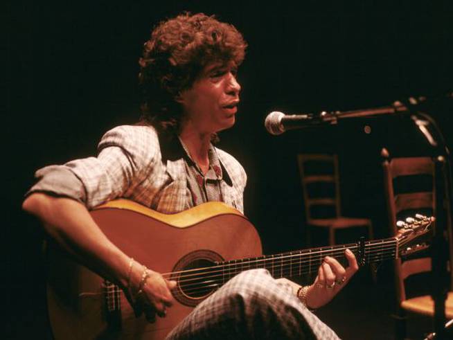 Camarón de la isla tocando la guitarra y cantando en un concierto de flamenco en Andalucía.