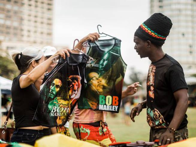 Varios fans de Bob Marley compran camisetas conmemorativas del artista en un festival de música reggae en Sudáfrica.