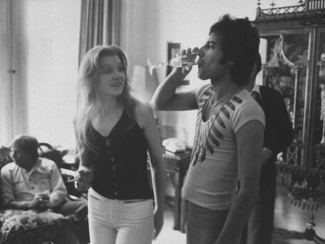 Rock singer  Freddie Mercury bebe una copa de champán junto a su entonces novia Mary Austin .