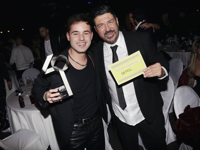 Tony Aguilar y DePol posan sonrientes. El artista catalán con su premio a Mejor Artista Del 40 al 1 y el presentador muestra el tarjetón con el nombre de DePol.