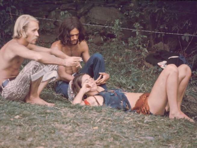 Tres asistentes al festival de Woodstock de 1969, descansando en la hierba.