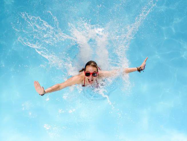 Una joven disfruta de un refrescante chapuzón en la piscina.