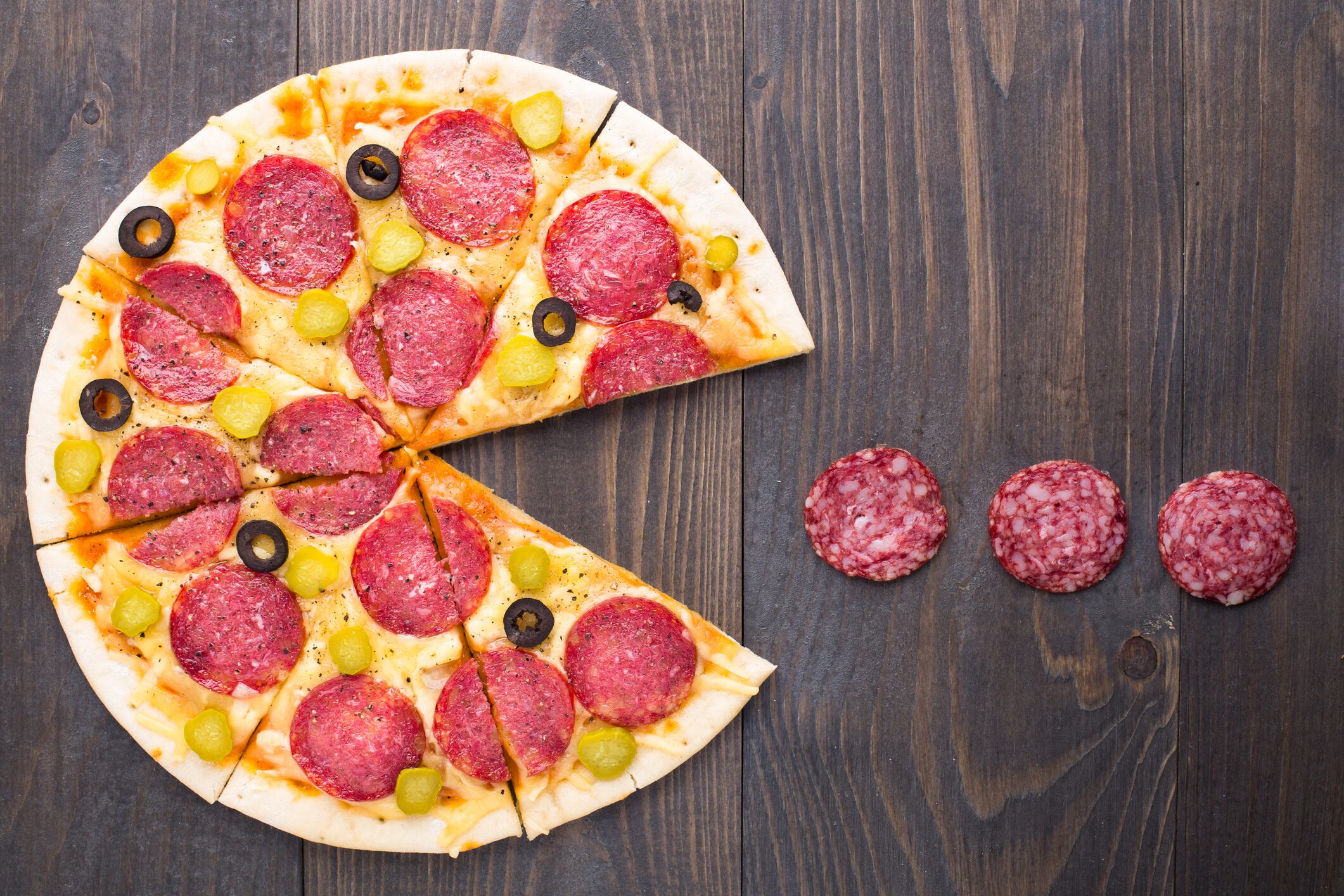 Pizza pacman eatting salami on a table