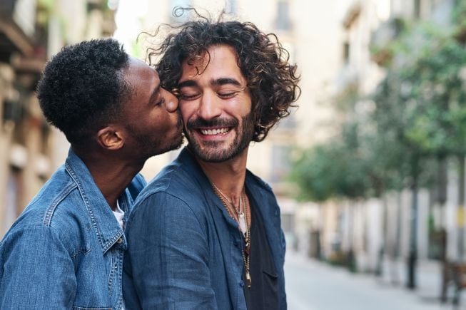 Un miembro de la pareja le da un beso en la mejilla a otro.