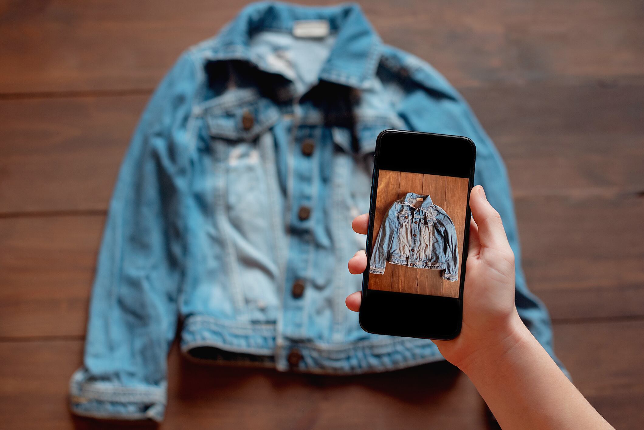 Woman taking photo of denim shirt on smartphone