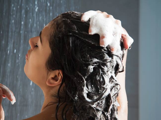 Una mujer se aplica el champú en el pelo