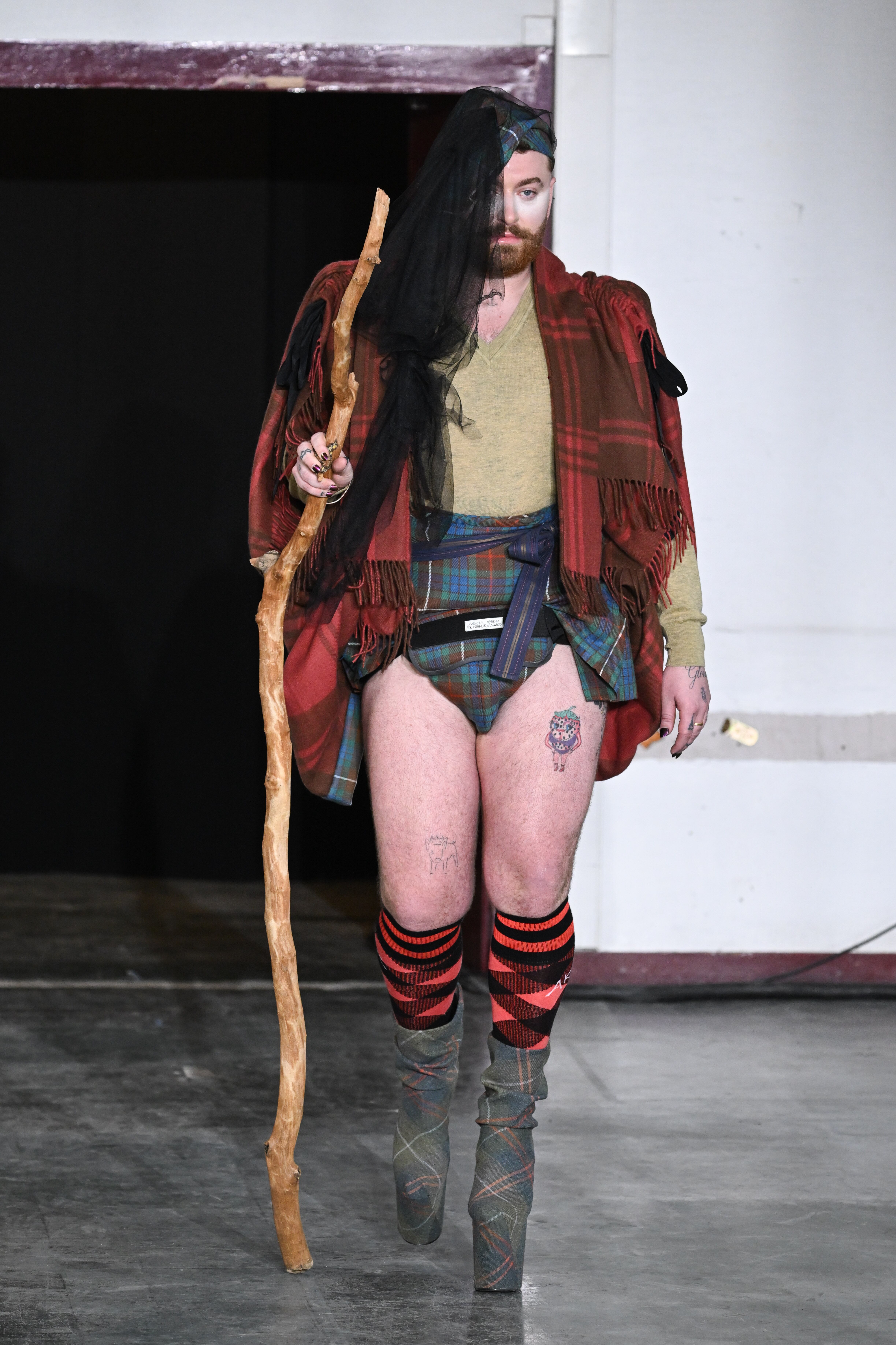 Si hay un modelo que ha llamado poderosamente la atención ha sido Sam Smith que debutaba en la pasarela gracias a Vivianne Westwood y su estilo tan peculiar. Uno de los dos looks que lució incluía una camisa verde color oliva con cuello en V, con un chal rojo a cuadros y una minifalda escocesa verde a la cintura. Todo completado con calcetines rojos a cuadros que llegaban hasta la rodilla y unas botas de plataforma del mismo estampado color verde oliva.