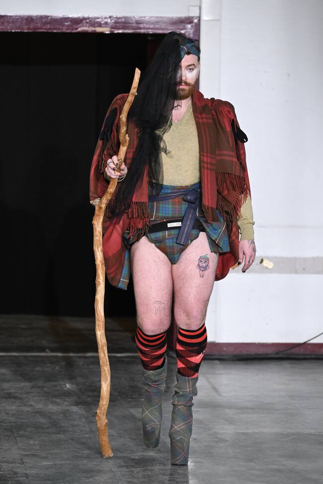 Si hay un modelo que ha llamado poderosamente la atención ha sido Sam Smith que debutaba en la pasarela gracias a Vivianne Westwood y su estilo tan peculiar. Uno de los dos looks que lució incluía una camisa verde color oliva con cuello en V, con un chal rojo a cuadros y una minifalda escocesa verde a la cintura. Todo completado con calcetines rojos a cuadros que llegaban hasta la rodilla y unas botas de plataforma del mismo estampado color verde oliva.