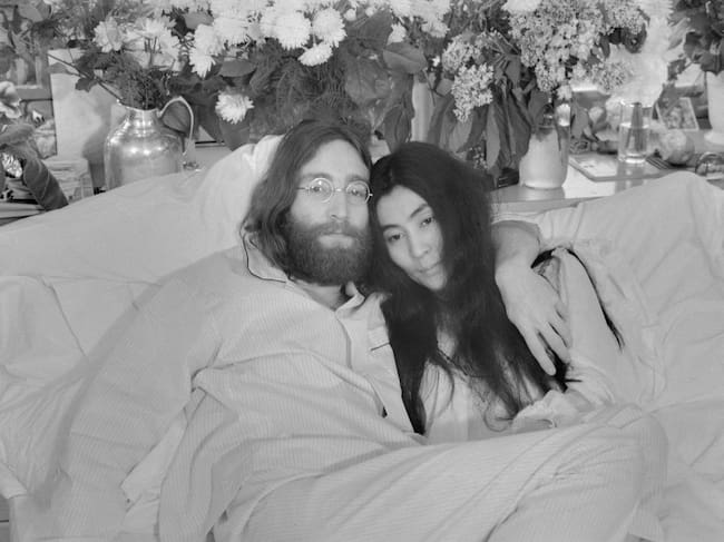 Yoko y John... El Beatle John Lennon y Yoko Ono —con quien llevaba casado tres meses cuando se tomó esta fotografía en Montreal, en junio de 1969— posan en la cama. Por aquel entonces, su primer álbum en solitario incluía canciones que hablaban de su amor por Yoko. Ambos ofrecieron ruedas de prensa desde la cama en varias ciudades bajo el lema «haz el amor y no la guerra». Lennon murió tiroteado el 8 de diciembre de 1980. En un comunicado emitido el 9 de diciembre, Yoko Ono declaró: «No habrá funeral para John. Más adelante esta semana fijaremos la hora de una vigilia silenciosa para rezar por su alma. Les invitamos a participar desde dondequiera que se encuentren en ese momento».