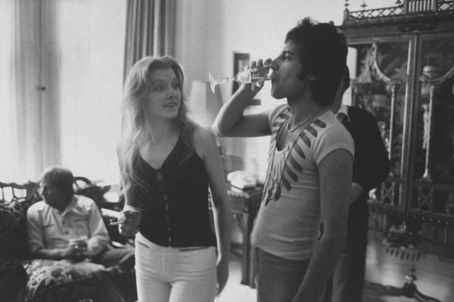 Rock singer  Freddie Mercury bebe una copa de champán junto a su entonces novia Mary Austin .