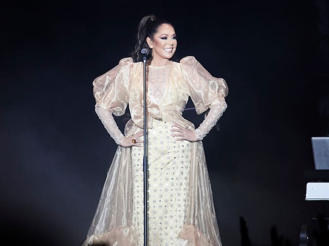 Isabel Pantoja durante su concierto en el Movistar Arena posando feliz con un vestido blanco.