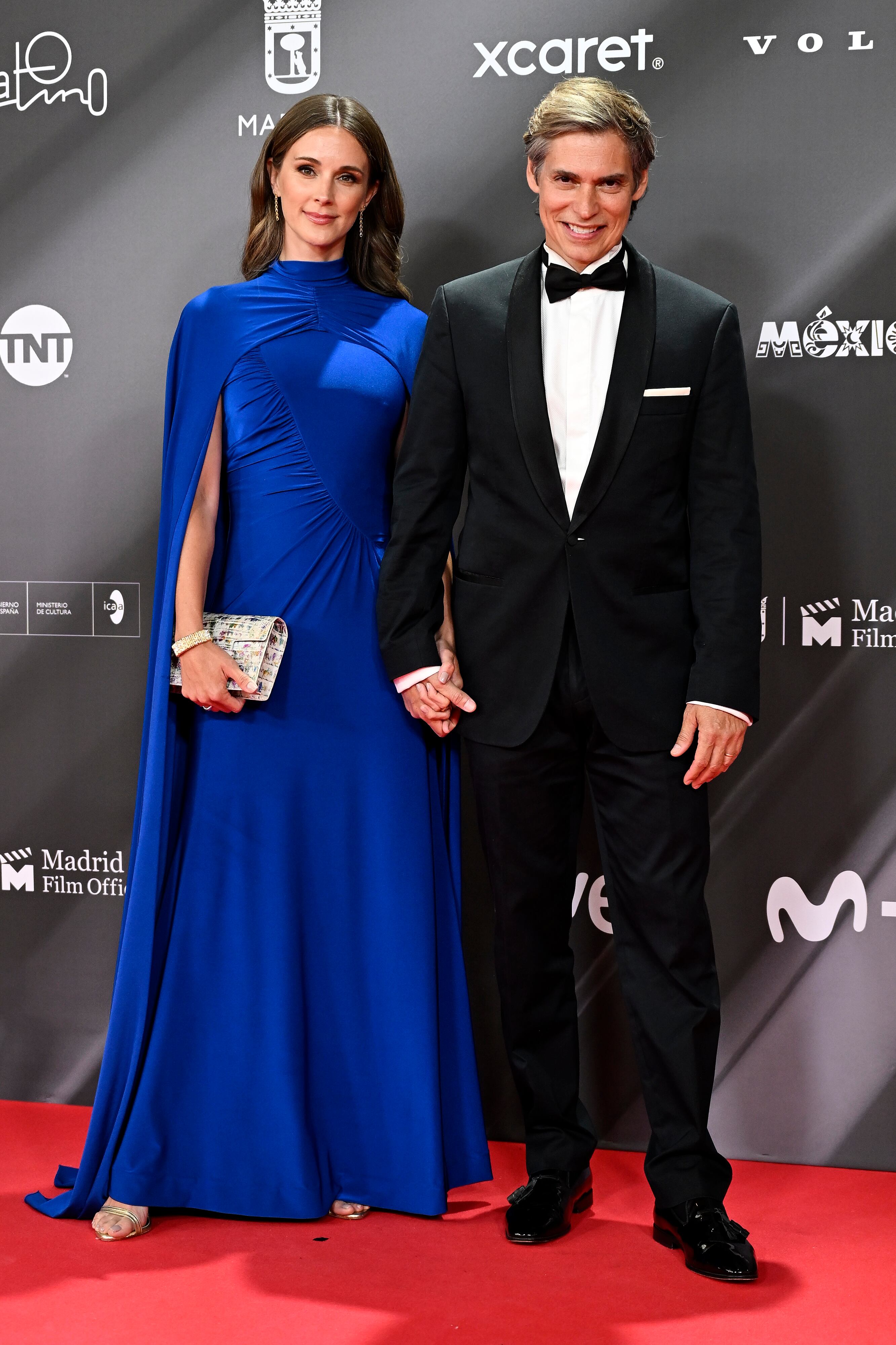 Otro músico con pajarita y acompañado de su mujer con un vestido con capa en azul Klein muy favorecedor.