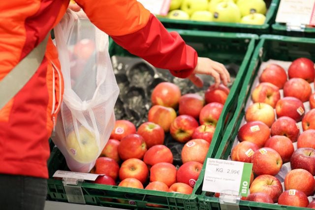 Una persona selecciona manzanas del supermercado.