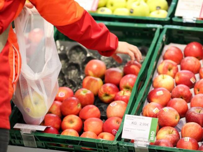 Una persona selecciona manzanas del supermercado.