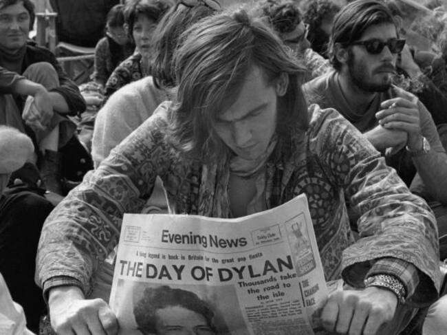 Un hombre lee el periódico en el que Bob Dylan ocupa la portada en el festival de la isla de Wight en 1969.