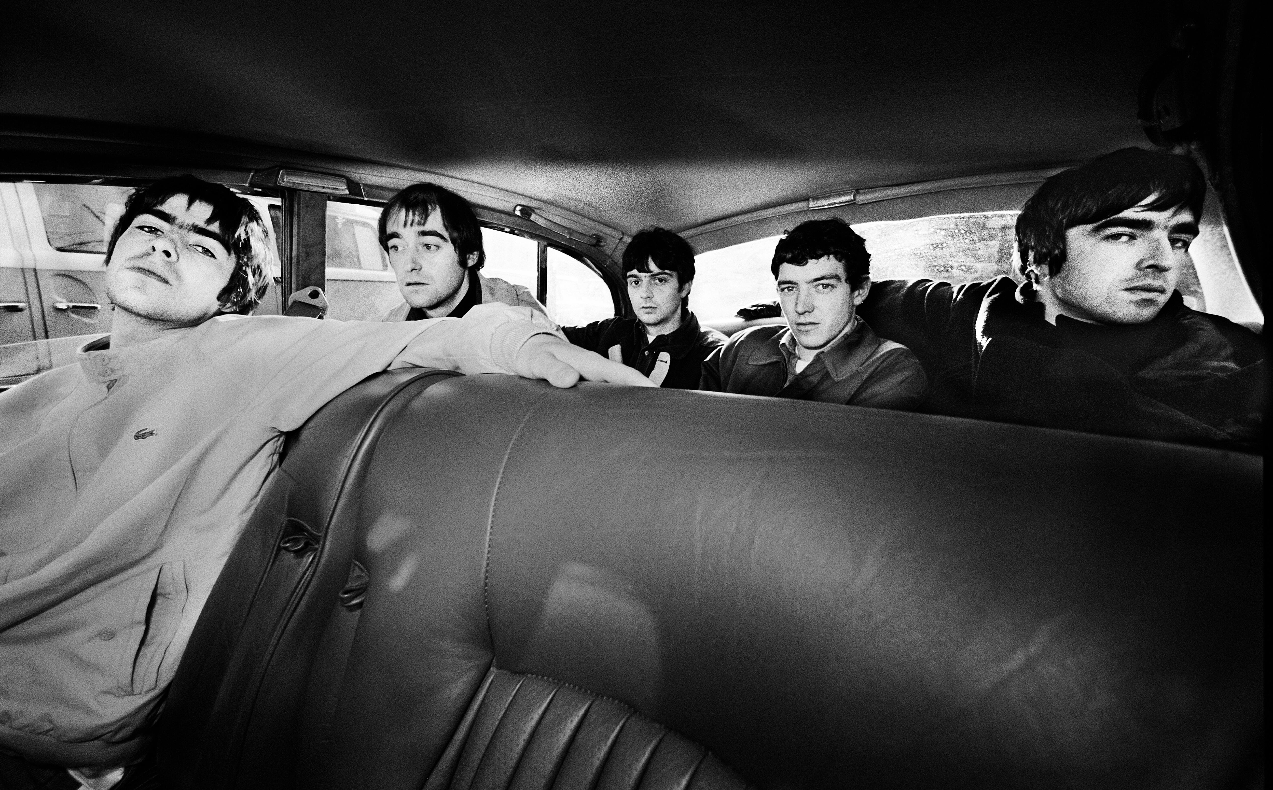 Retrato grupal de la banda de rock británica Oasis en un Jaguar XJ6, Manchester, Reino Unido, 30 de noviembre de 1993. De izquierda a derecha: Liam Gallagher, Paul Arthurs (alias Bonehead), Paul McGuigan, Tony McCarroll, Noel Gallagher. (Foto de James Fry/Getty Images)