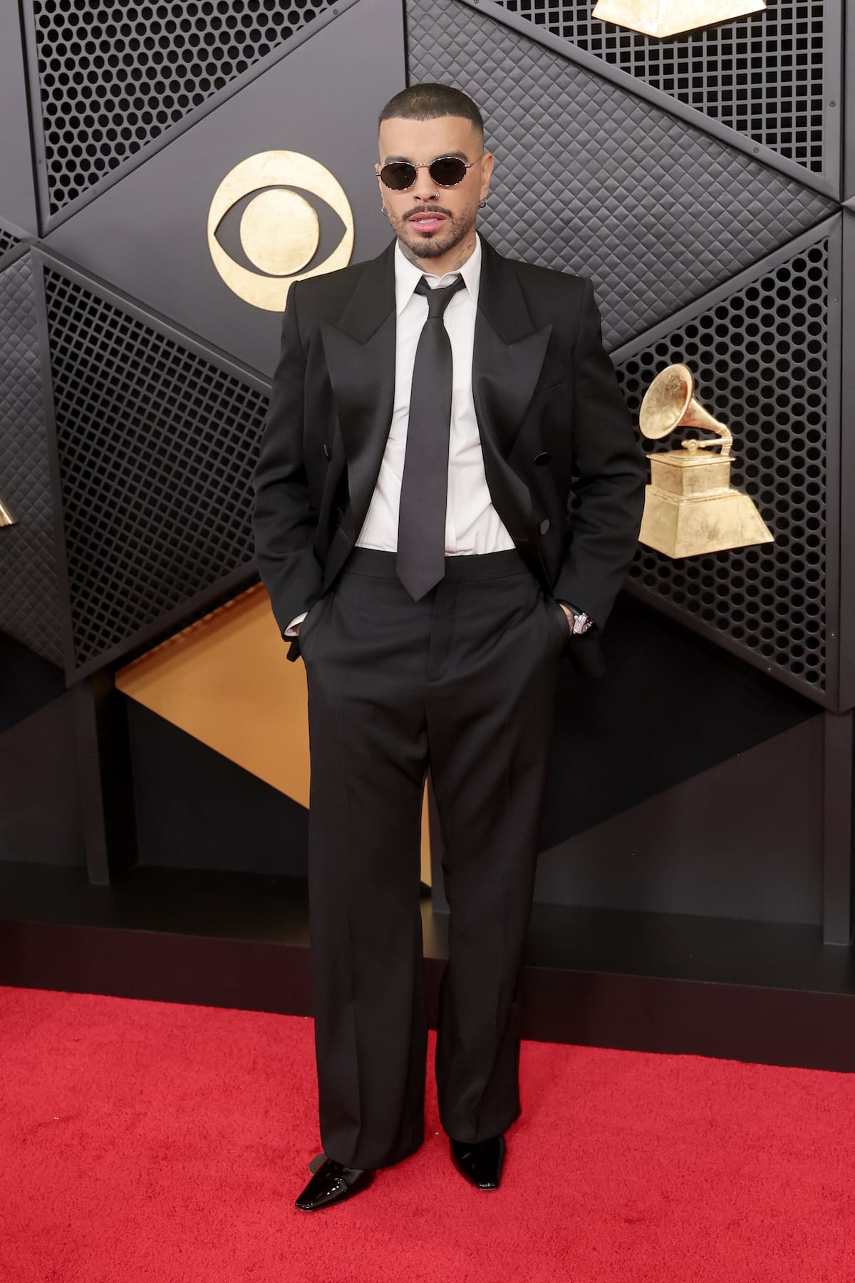 Un elegante Rauw Alejandro con traje negro y corbata que no se quitó las gafas de sol para posar.