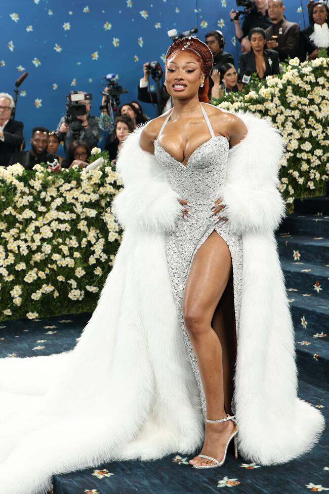 Megan Thee Stallion lucía un Michael Kors plateado con una abertura alta en el costado y adornos de encaje floral con un maxi abrigo de pelo blanco.