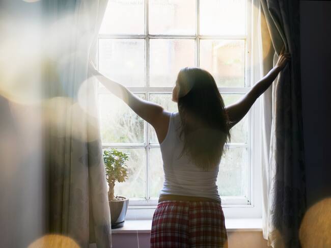 Una mujer abriendo las cortinas