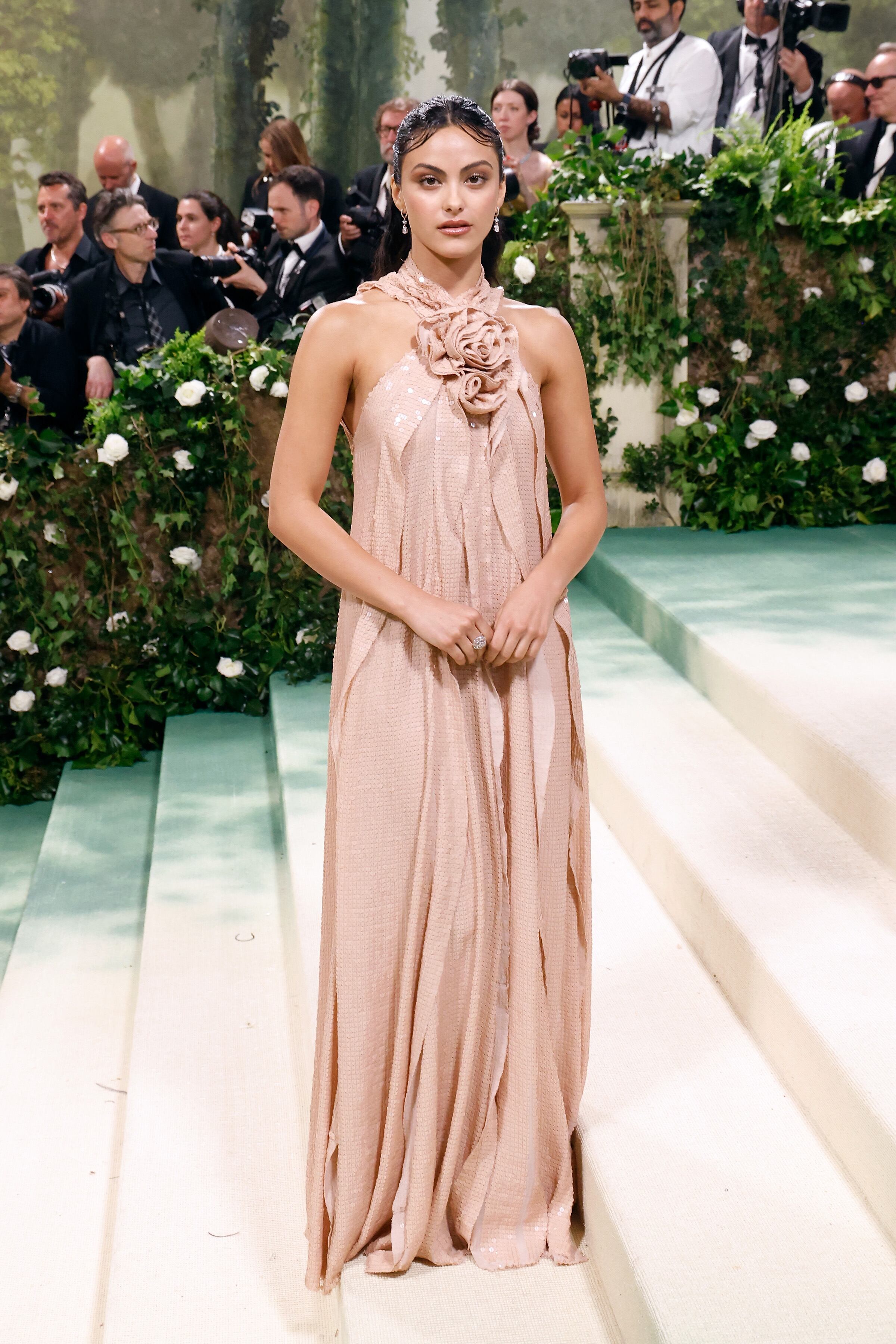 La rosa fue una de las flores más homenajeadas en este jardín de la MET Gala y fue la que escogió Camila Mendes con este vestido de cuello halter y flor de tela en color rosa palo, con volantes que dibujan su silueta diseñado por Joseph Altuzarra.