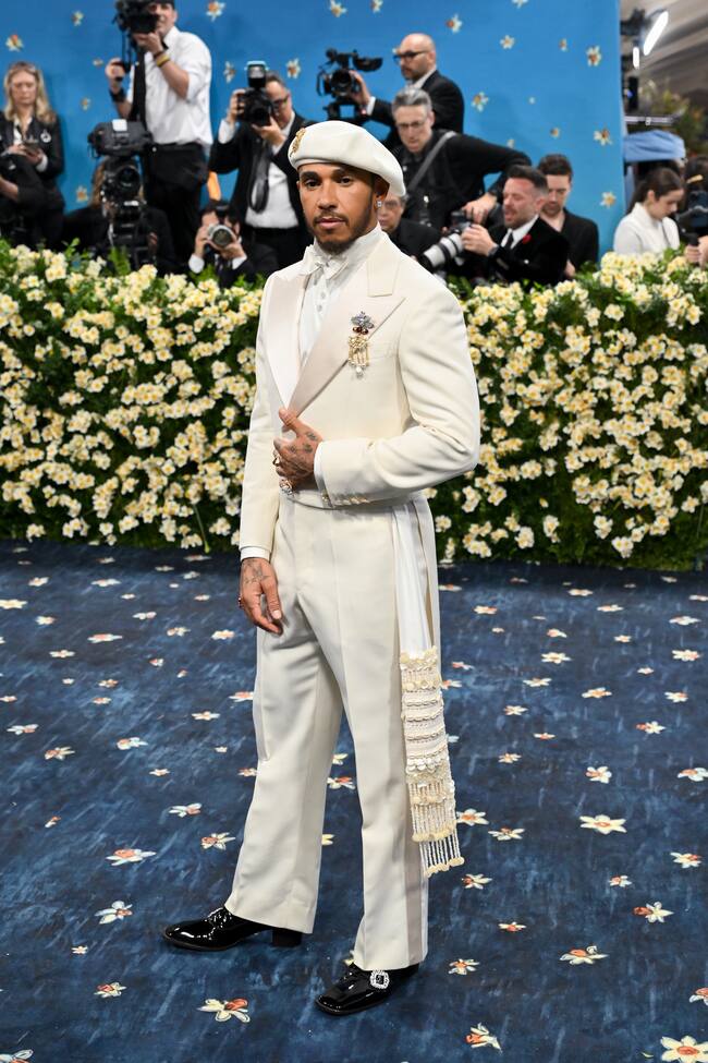 Lewis Hamilton lució un esmoquin marfil con chaqueta corta cuyo significado explicó en Instagram: “El color marfil denota pureza y estatus; las cauris pasan de mano en mano, la banda real se vuelve chamánica”.