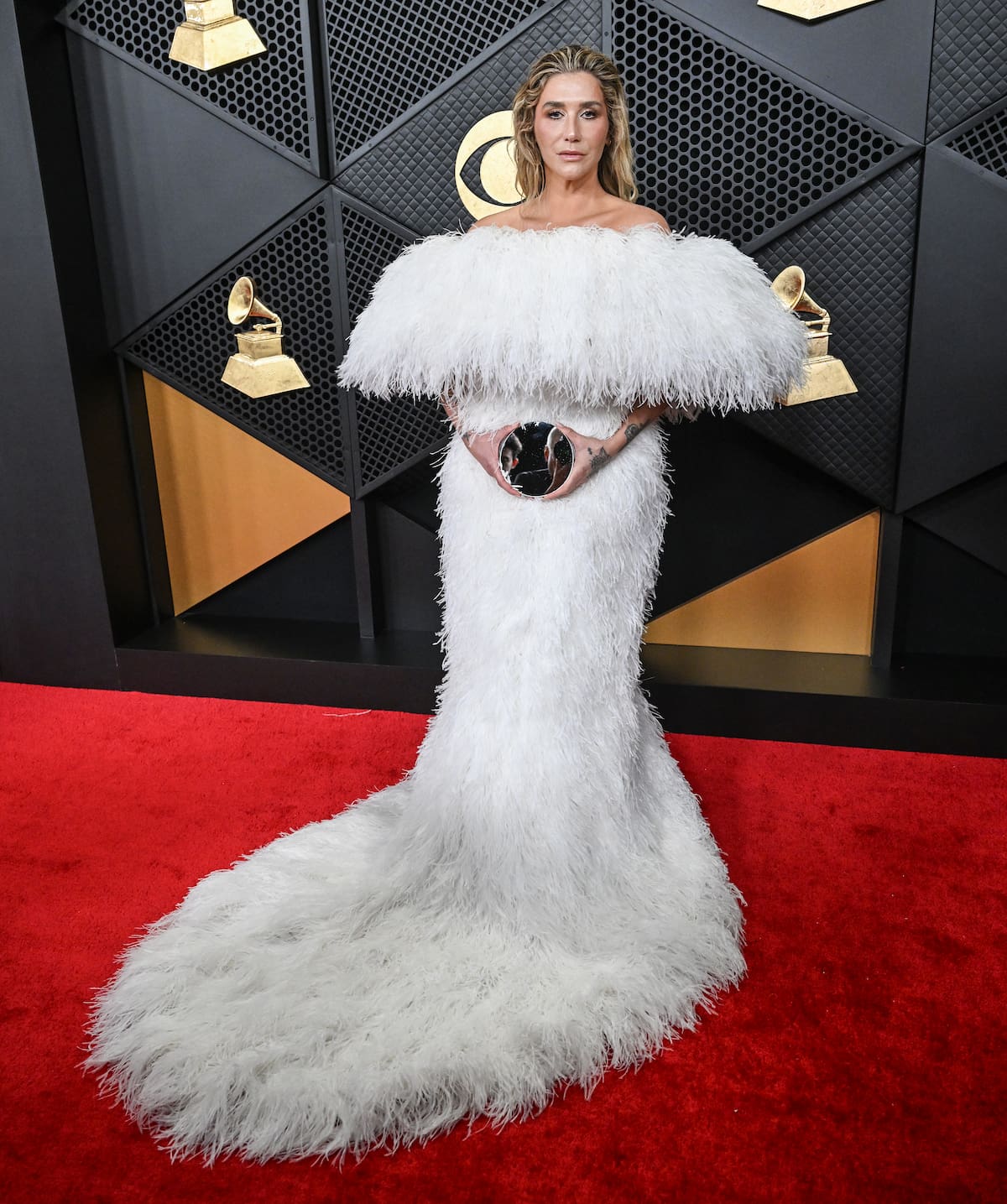 Kesha llegaba con un voluminoso vestido blanco de plumas blanco de Atelier Biser. Y un aspecto de no make up con efecto wet en el peinado.
