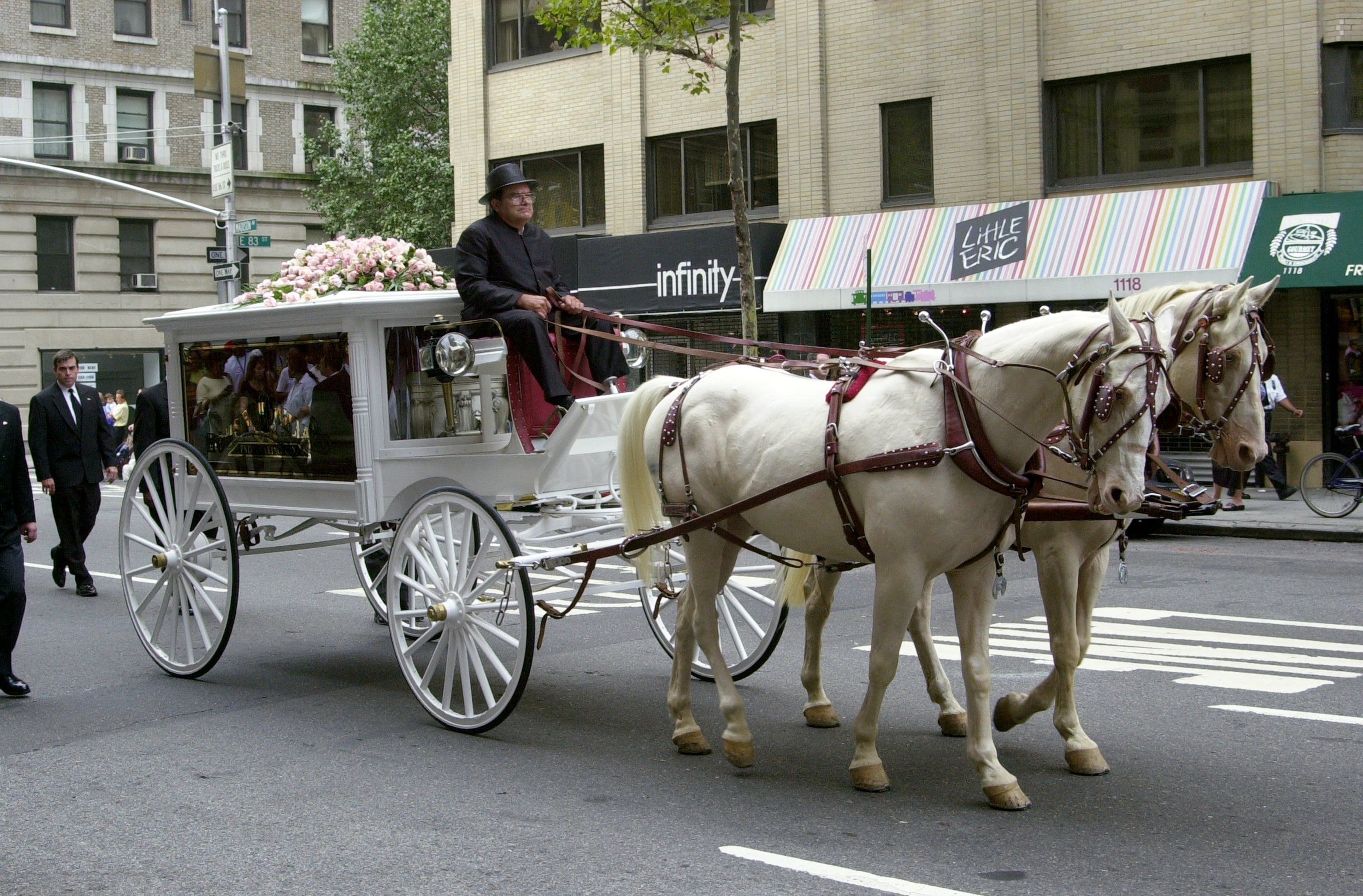 ESTADOS UNIDOS - HACIA 2001: Un carruaje antiguo con paneles de vidrio, tirado por una pareja de caballos de color crema, transporta el féretro de la estrella de R&B Aaliyah por Madison Avenue, desde la funeraria Frank E. Campbell (en la calle 81 Este) hasta la iglesia católica romana de San Ignacio de Loyola (en la intersección de la calle 84 Este y Park Avenue). La cantante y actriz, de 22 años, falleció el sábado anterior en un accidente aéreo en las Bahamas, donde se encontraba rodando un videoclip. El coche fúnebre está adornado con rosas de su color favorito: el rosa. (Foto de Thomas Monaster/Archivo del NY Daily News vía Getty Images)