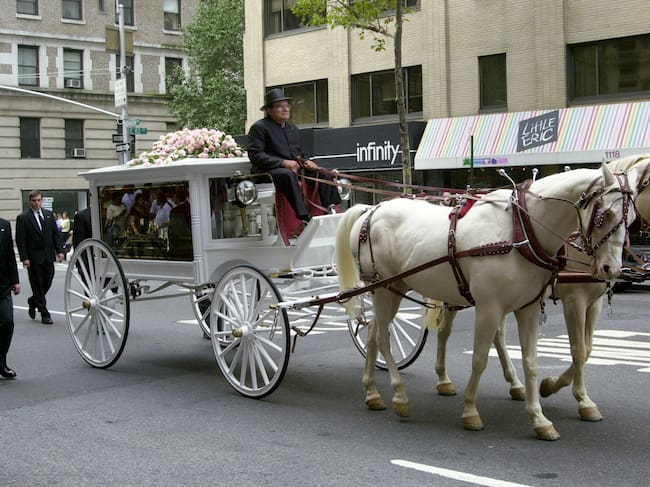 ESTADOS UNIDOS - HACIA 2001: Un carruaje antiguo con paneles de vidrio, tirado por una pareja de caballos de color crema, transporta el féretro de la estrella de R&B Aaliyah por Madison Avenue, desde la funeraria Frank E. Campbell (en la calle 81 Este) hasta la iglesia católica romana de San Ignacio de Loyola (en la intersección de la calle 84 Este y Park Avenue). La cantante y actriz, de 22 años, falleció el sábado anterior en un accidente aéreo en las Bahamas, donde se encontraba rodando un videoclip. El coche fúnebre está adornado con rosas de su color favorito: el rosa. (Foto de Thomas Monaster/Archivo del NY Daily News vía Getty Images)