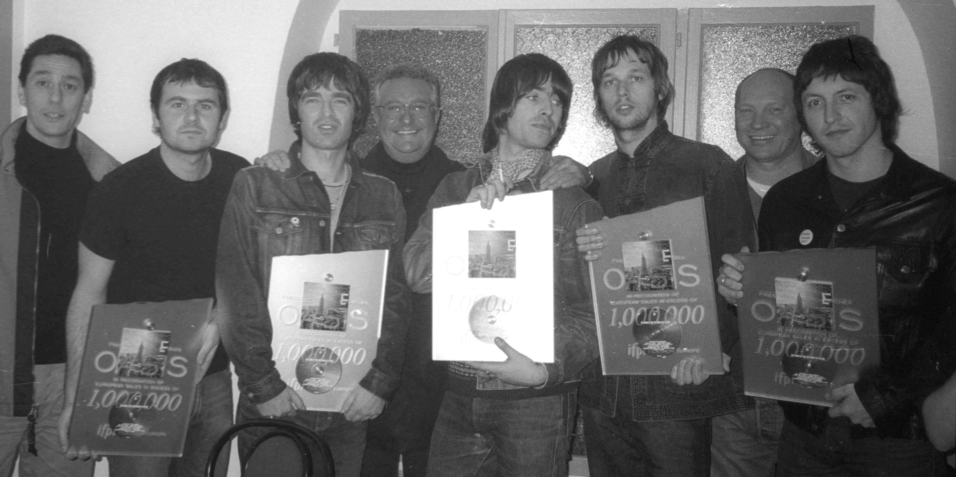 Noel Gallagher (nacido en 1967), cantautor británico, Liam Gallagher (nacido en 1972), cantante y músico británico, y los integrantes de su banda de rock Oasis, reciben un disco de diamante en su camerino del Bataclan. París (distrito 11), 21 de marzo de 2000. (Foto de Christian Rose/Roger Viollet vía Getty Images)