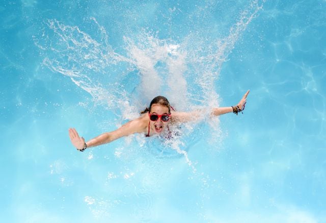 Una joven disfruta de un refrescante chapuzón en la piscina.