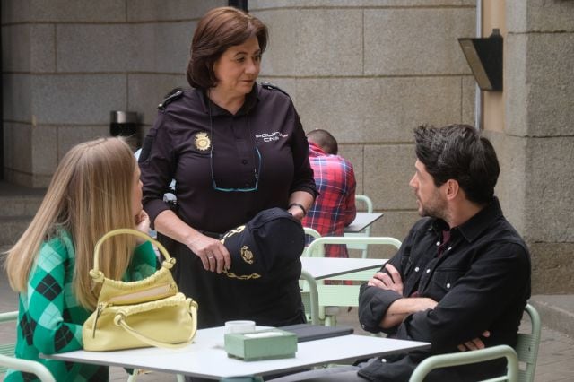 Claudia Mirales charla con algunos de los agentes de policía de la comisaría en una terraza.