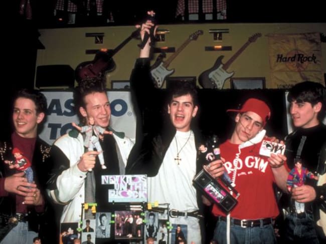 Los miembros de New Kids on the Block sosteniendo el famoso merchandising NKOTB.
