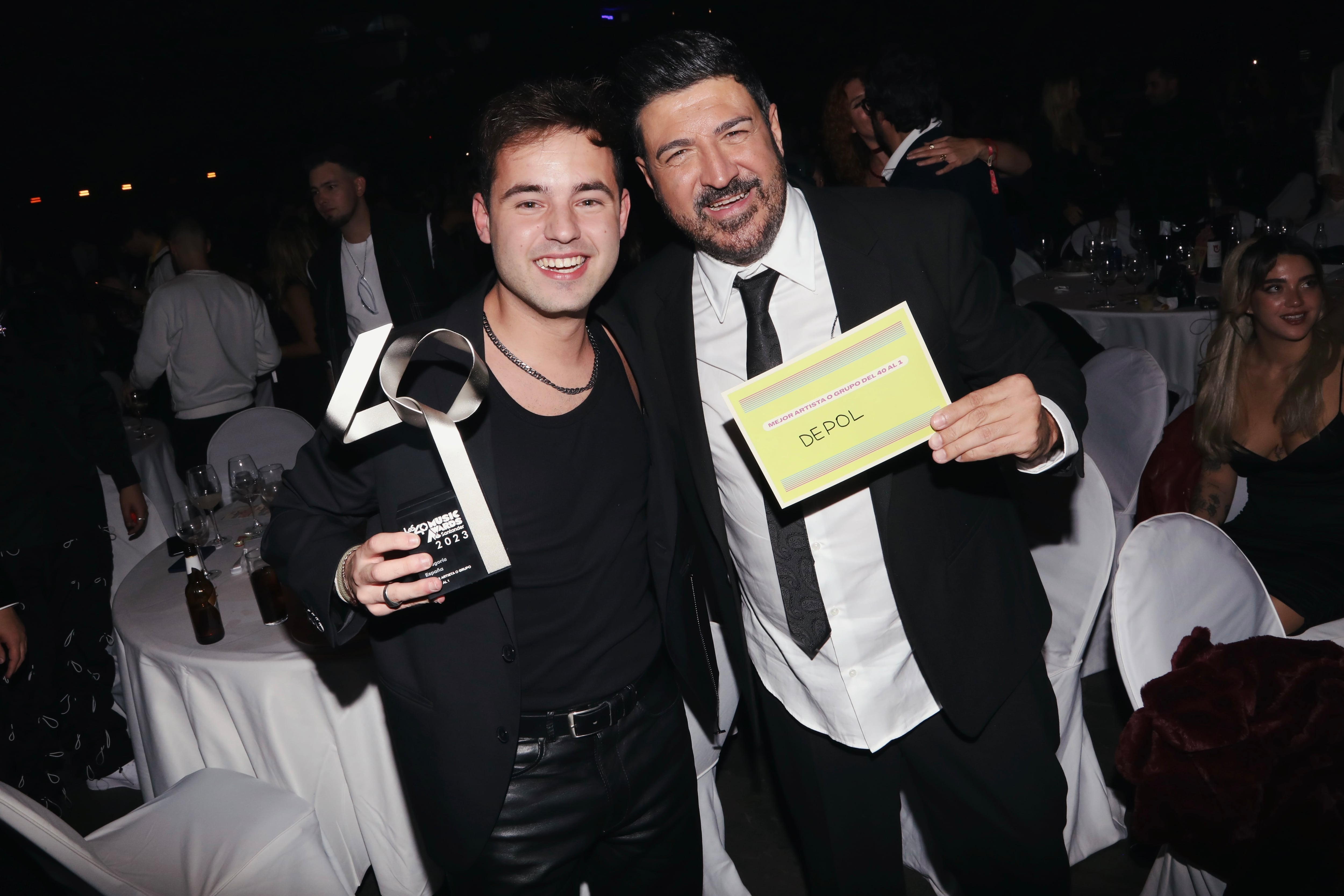 Tony Aguilar y DePol posan sonrientes. El artista catalán con su premio a Mejor Artista Del 40 al 1 y el presentador muestra el tarjetón con el nombre de DePol.