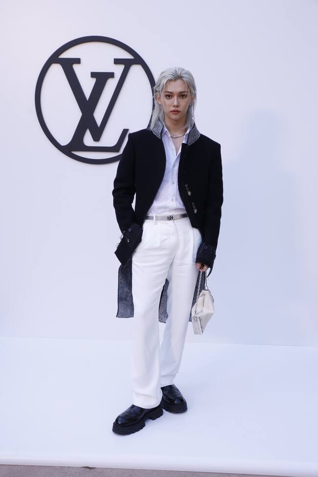 El cantante de K-Pop del grupo Stray Kids ha dejado claro que los bolsos no son solo para ellas y Louis Vuitton aboga por ello. Ha llegado con su larga melena rubio platino a juego con su camisa y pantalón de blanco impoluto. El contraste lo ponía el abrigo con detalles brillantes en el cuello.