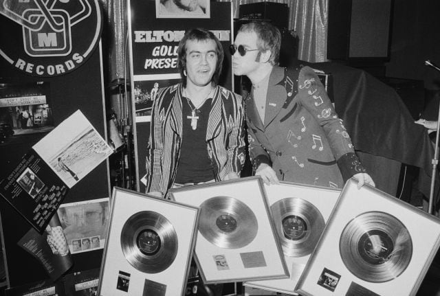 Elton John y su colaborador Bernie Taupin, recogiendo cuatro discos de oro como reconocimiento a su trabajo, en 1973.