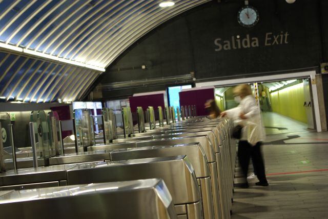 Una mujer cruza los tornos de una estación de tren.