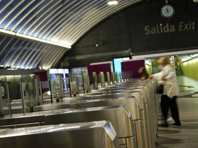 Una mujer cruza los tornos de una estación de tren.