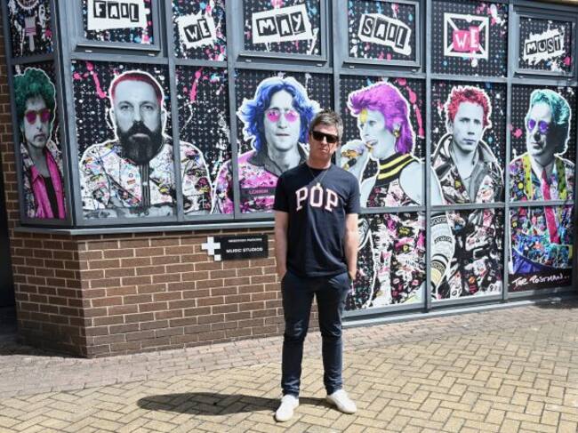 Noel Gallagher posa delante del mural en el que que están sus músicos favoritos: Bob Dylan, Andy Weatherall, David Bowie, John Lydon, John Lennon y Tony Wilson.