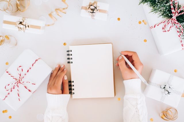 Una chica intenta escribir en una libreta en blanco sus Propósitos de Año Nuevo.