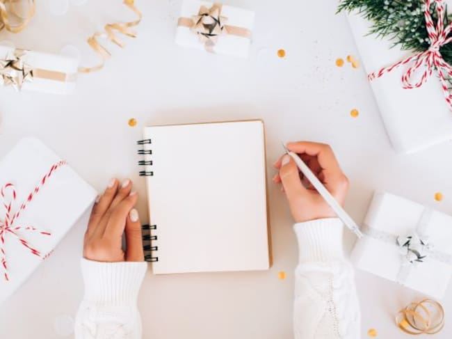 Una chica intenta escribir en una libreta en blanco sus Propósitos de Año Nuevo.