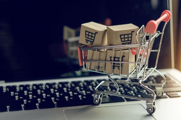 Shopping online concept - Parcel or Paper cartons with a shopping cart logo in a trolley on a laptop keyboard. Shopping service on The online web. offers home delivery.