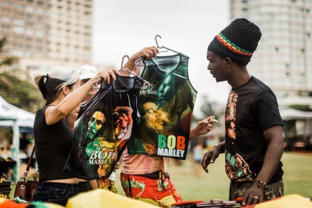 Varios fans de Bob Marley compran camisetas conmemorativas del artista en un festival de música reggae en Sudáfrica.