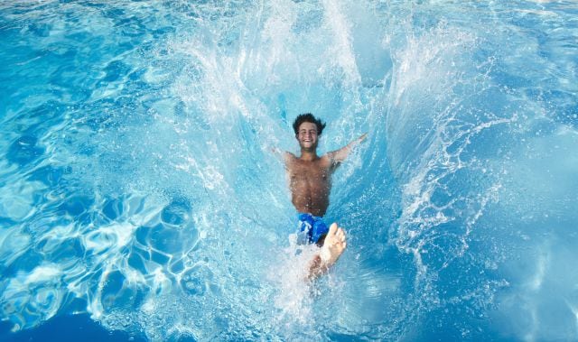 Un joven se tira a la piscina para refrescarse y disfrutar de ratos muy agradables junto a los suyos.