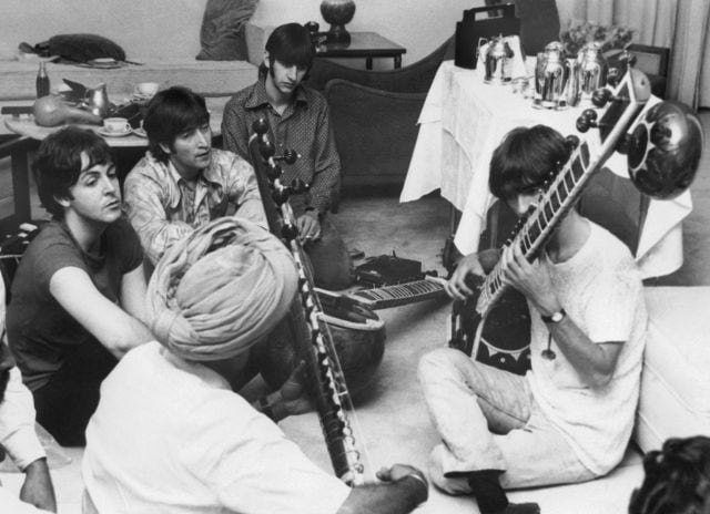 George Harrison recibe instrucciones de cómo tocar el sitar, mientras el resto de la banda observa.