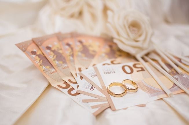 Varios billetes de 50 euros junto con las alianzas de boda.