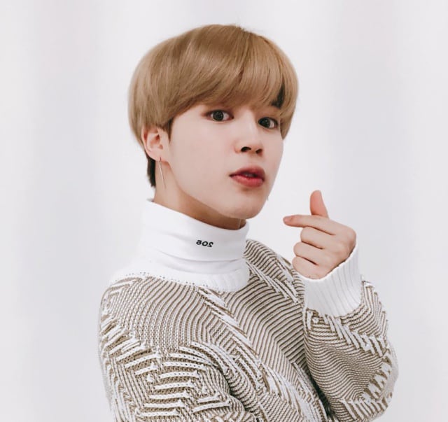 Jimin, integrante de BTS, haciendo un corazón con los dedos para sus fans