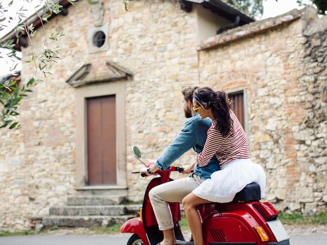 Una pareja disfruta de su viaje en una Vespa / Westend61 (Getty Images)